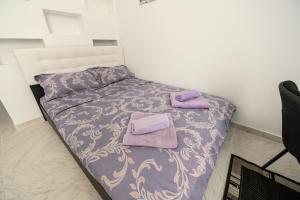 a bed with purple sheets and purple towels on it at Etiquette Studios Mamaia in Constanţa