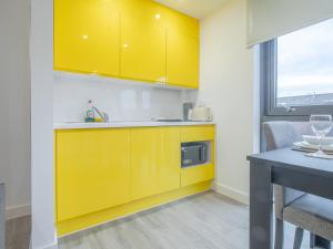 a kitchen with yellow cabinets and a table at Modern Studio Serviced Apartments Sheffield City Centre - Netflix, WiFi, Digital TV in Sheffield