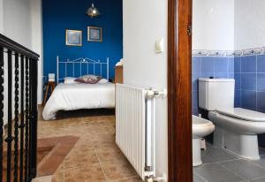 a bathroom with a toilet and a bed with blue walls at LA CASICA in Segorbe