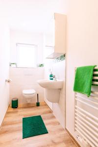 a bathroom with a toilet sink and a green rug at Pension Dorfliebe in Sondershausen