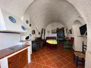 eine Küche und ein Wohnzimmer mit einem Tisch im Zimmer in der Unterkunft Cuevas Pedro Antonio de Alarcon in Guadix