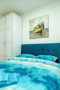 ein Schlafzimmer mit einem blauen Bett und einem Gemälde an der Wand in der Unterkunft Apartman Happy day Divčibare in Divčibare