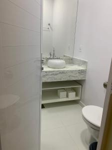 a white bathroom with a sink and a toilet at Suite Starfish in Guarujá +13 photos