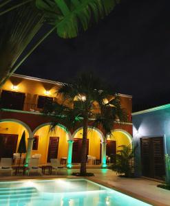 a resort with a palm tree and a swimming pool at night at Merida Santiago Hotel Boutique in Mérida