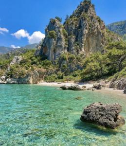 a beach with rocks in the water and a mountain at Dadya Villa 1 - Villa with private pool - 750m distance to the beach in Datca