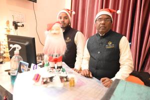 two men wearing santa claus hats standing in front of a table at Hotel Comfort and Terrace Lounge in Deoghar