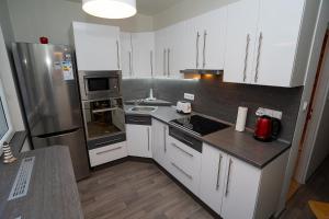 a kitchen with white cabinets and a stainless steel refrigerator at Apartment Ivet in Hazlov