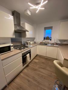 a kitchen with white cabinets and a stove top oven at Luxury Riverside 2 bedroomed Apartment with Balcony in Newport +35 photos