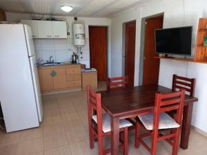 cocina con mesa de madera, sillas y nevera en Cabañas Dayma en Trapiche