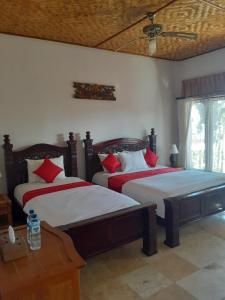 a bedroom with two beds with red pillows at Double One Villas in Amed