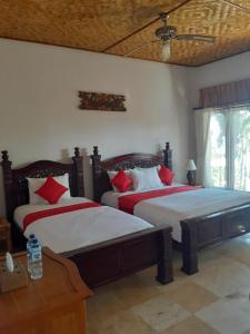 1 dormitorio con 2 camas y almohadas rojas en Double One Villas, en Amed
