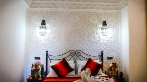 una camera da letto con un letto con cuscini rossi di Dar Habache a Marrakech
