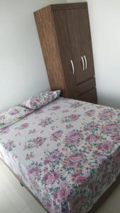 ein Bett mit einem geblümten Bettlaken und einem Schrank in der Unterkunft Recanto das Gerais in Passos