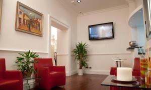a waiting room with red chairs and a flat screen tv at Gambrinus Hotel in Rome