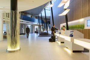 a lobby of an airport with a man standing at a counter at Novotel Hannover in Hannover