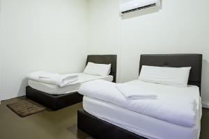 two beds in a room with white sheets at We Love GuestHouse in George Town