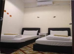 two beds in a room with white walls at We Love GuestHouse in George Town