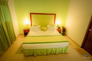 a bedroom with a large bed with green sheets and pillows at Seethawaka Regency in Avissawella
