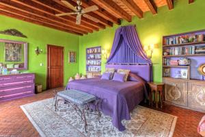 サンミゲル・デ・アジェンデにあるCasa Schuck Boutique Hotelの緑の壁のベッドルーム1室(紫色のベッド1台付)