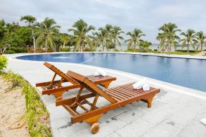 a swimming pool with two wooden benches next to a table at Casa Maya Hotel in ThÃ´n Báº£o An