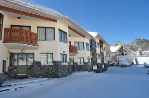 a building with snow on the ground in front of it at Salzburg Apartments in Perisher Valley