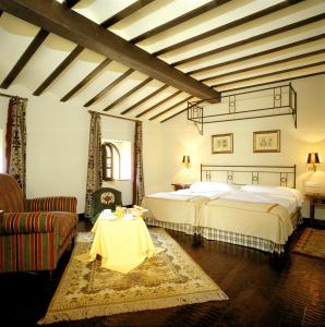 1 dormitorio con 2 camas, mesa y sofá en Parador de Santillana Gil Blas, en Santillana del Mar