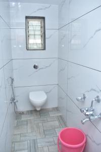 La salle de bains blanche est pourvue de toilettes et d'une fenêtre. dans l'établissement HOTEL SAI VISHVA KARMA, à Shirdi