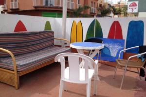 a bench and chairs sitting next to a wall with surfboards at KAKTUS BEACH House in Corralejo