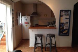 eine Küche mit zwei Barhockern und einem Kühlschrank in der Unterkunft KAKTUS BEACH House in Corralejo