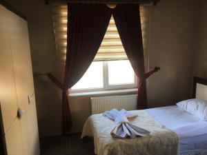 a bedroom with a bed and a window with a robe on it at Fimaj Residence & Hotel in Kayseri