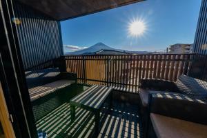 uma varanda com um banco e vista para as montanhas em 02 Resort Club -蒼SOU- em Fujikawaguchiko