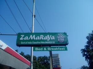 a green sign for a restaurant on a street at ZaMaRaYa Bed & Breakfast in Angamaly