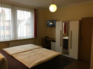 a bedroom with a bed and a tv and a window at Hotel Sieme in Osnabrück