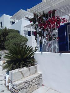 a white house with red flowers on a wall at Nicos Studios & Apartments in Logaras