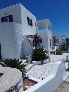 a white building with plants in front of it at Nicos Studios & Apartments in Logaras