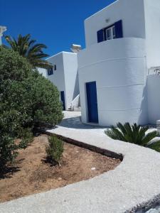 un bâtiment blanc avec des portes et des plantes bleues devant lui dans l'établissement Nicos Studios & Apartments, à Logaras