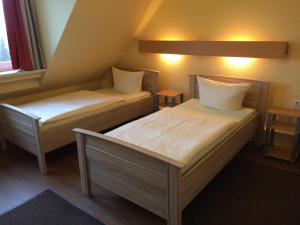 two beds in a small room with two tables at Hotel Sieme in Osnabrück