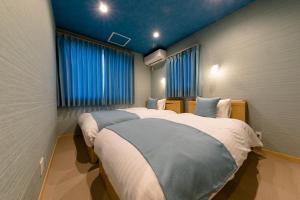 a bedroom with two beds and blue curtains at 02 Resort Club -蒼SOU- in Fujikawaguchiko