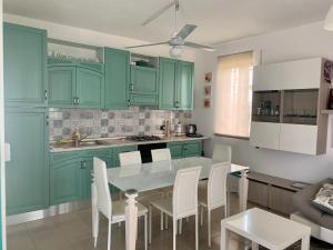 a kitchen with green cabinets and a table and chairs at Acquamarina Apartment in Marzamemi