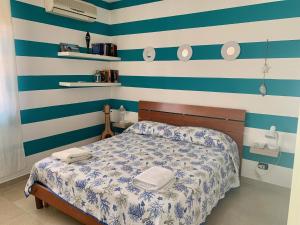 a bedroom with a bed with blue and white stripes at Acquamarina Apartment in Marzamemi