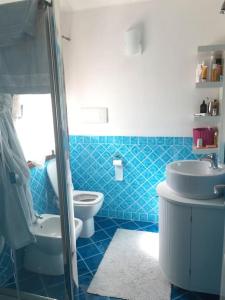 een blauw betegelde badkamer met een toilet en een wastafel bij VILLA VISTA MARE INFINITY POOL in Marinella