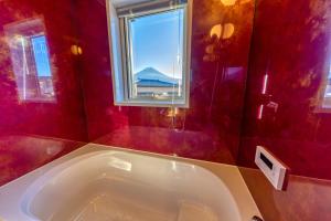 a bath tub in a red bathroom with a window at 02 Resort Club -蒼SOU- in Fujikawaguchiko