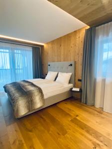duże łóżko w pokoju z drewnianymi podłogami i oknami w obiekcie Florisa Mountain Penthouse w mieście San Vigilio di Marebbe