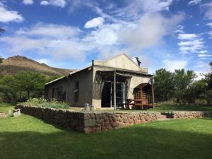a small house in a field with a stone wall at Waterval farmstay in Graaff-Reinet