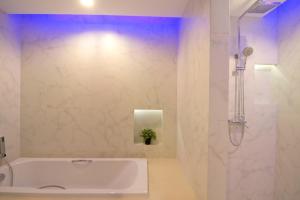a white bathroom with a tub and a shower at The Stay Hotel "SHA Certified" in Pattaya
