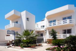 a white apartment building with white balconies and palm trees at Anna Katerina Apartments in Platanias