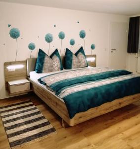 a bedroom with a bed with blue pillows and trees on the wall at Sand 4 in Stanzach