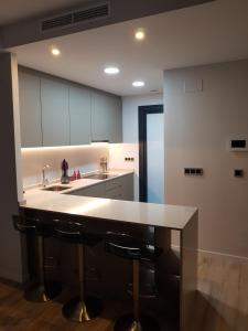 cocina con fregadero y encimera con taburetes en ROMERO APARTMENTS-SUNSET WAVES-BENIDORM, en Benidorm