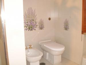 a bathroom with a toilet and purple flowers on the wall at Il Glicine di Carmen in Fondi