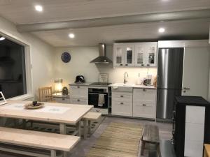 a kitchen with white cabinets and a table and a refrigerator at Villa Saagala by Tornio River in Tornio